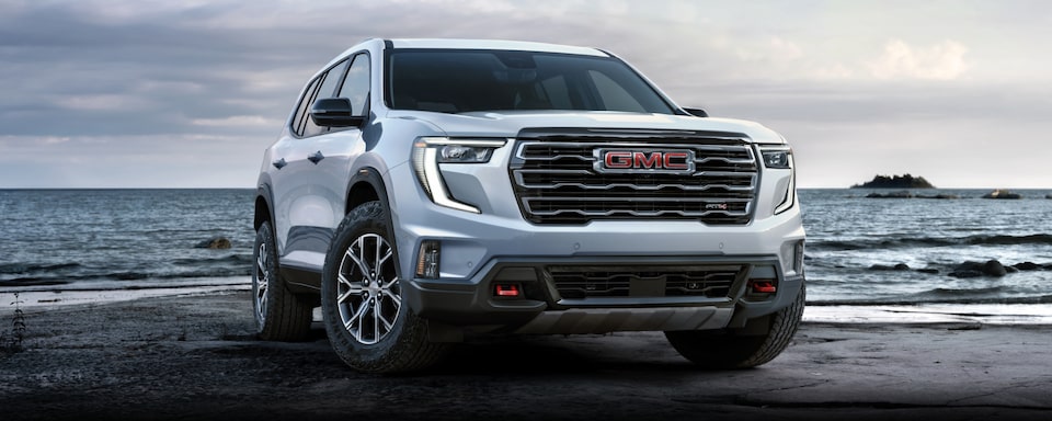 Front-side view of the 2024 GMC Acadia AT4 parked by the beach.