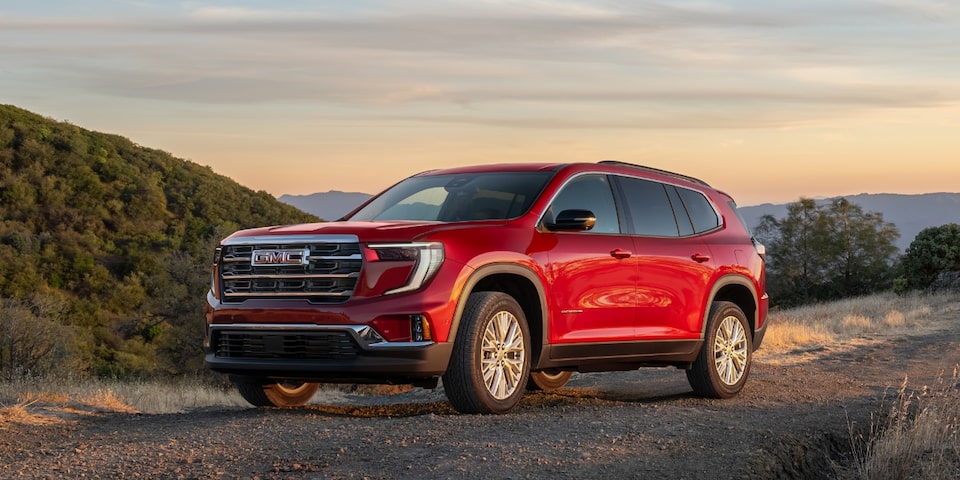 Side view of the 2024 GMC Acadia Elevation driving alone on a hillside road.