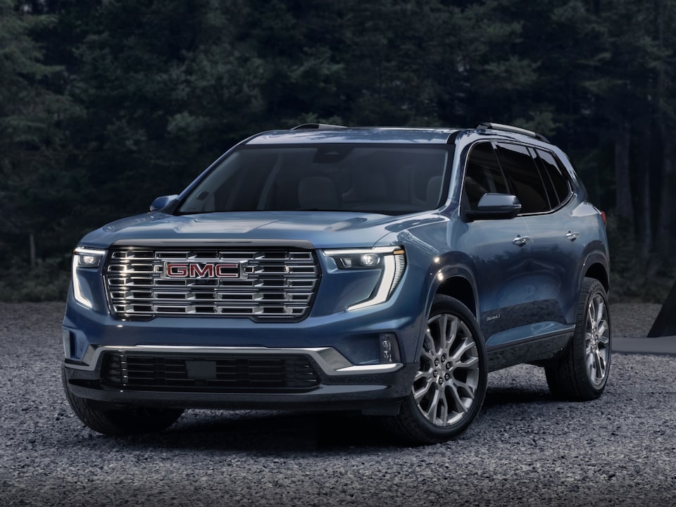 Front-side view of the 2024 GMC Acadia Denali parked near the trees.