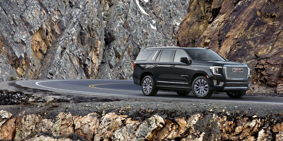 2024 GMC Yukon Denali driving alone on a mountain road.