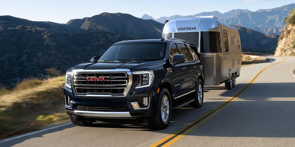 2024 Yukon Denali towing a vehicle on a mountain road.