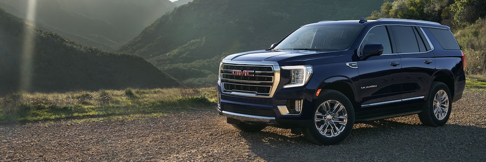 2024 GMC Yukon SLT driving on a hillside terrain.