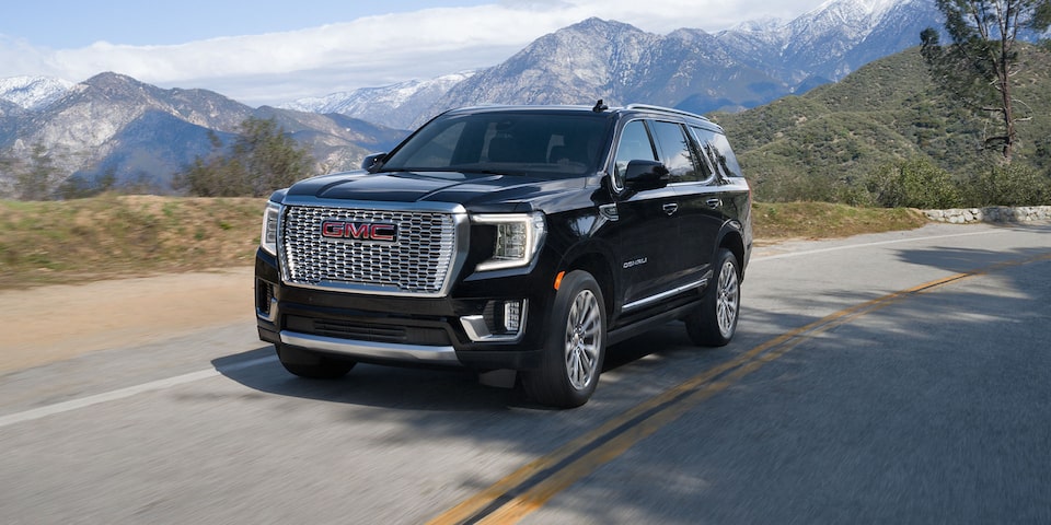 Front view of the 2024 Yukon Denali driving alone on a mountain road.