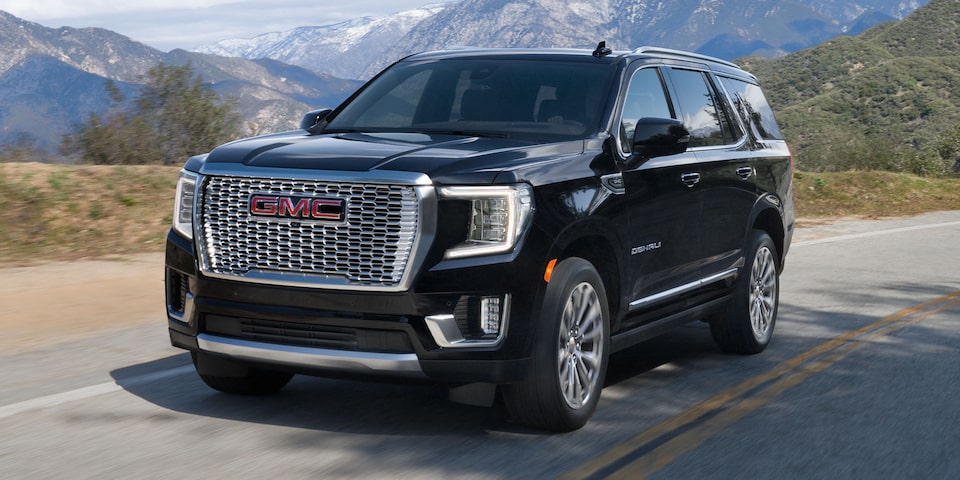 2024 GMC Yukon Denali driving alone on a hillside road.