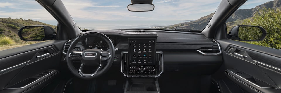 Driver's view of steering wheel and infotainment screen on the 2025 GMC Acadia Elevation.