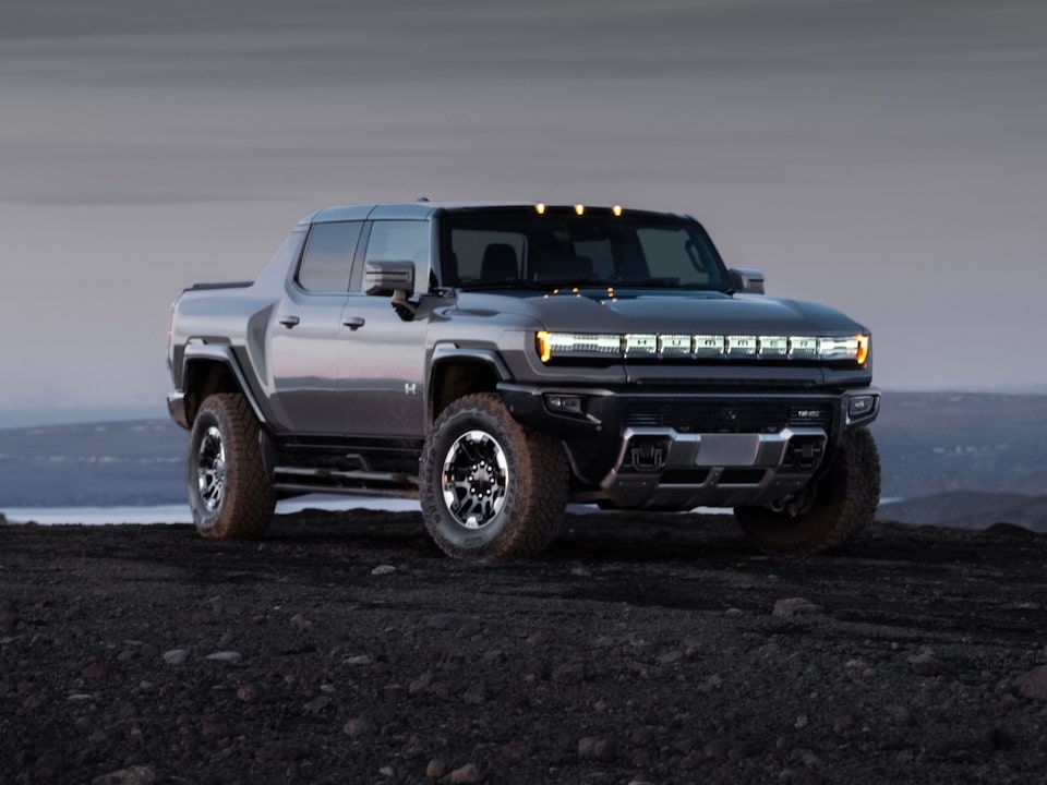 Front three-quarters view of the 2025 GMC Hummer EV Pickup Truck parked alone at dusk.