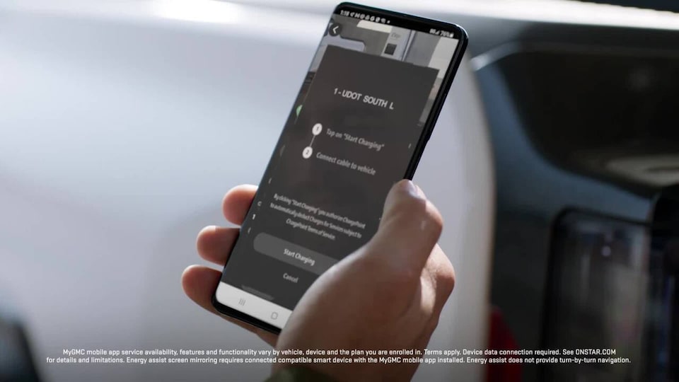 A person holding a phone with the GMC App opened showing charging options for the 2025 GMC Hummer EV SUV.