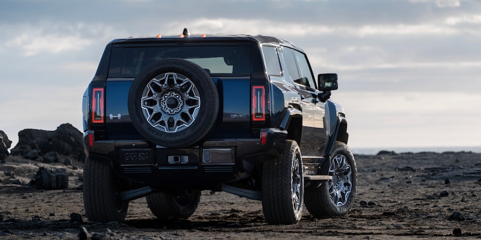 Rear view of a black 2025 GMC Hummer EV SUV parked under an evening sky.