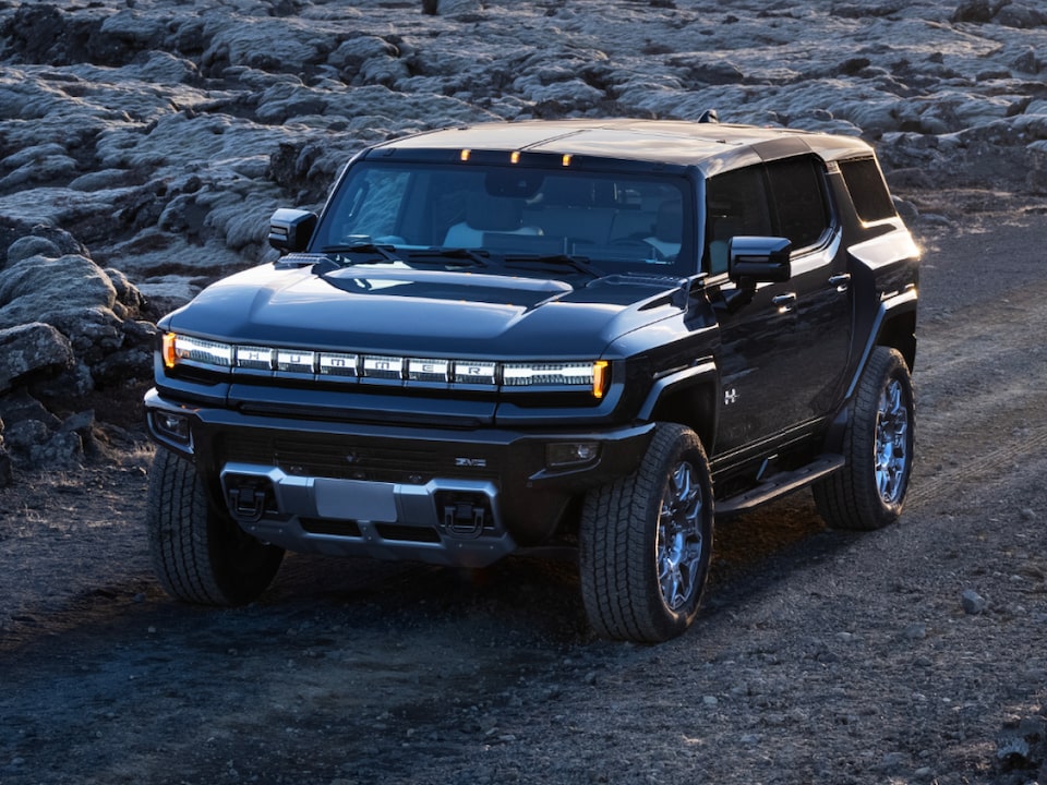 Front three-quarters view of the 2025 GMC Hummer EV Pickup Truck parked alone at dusk.