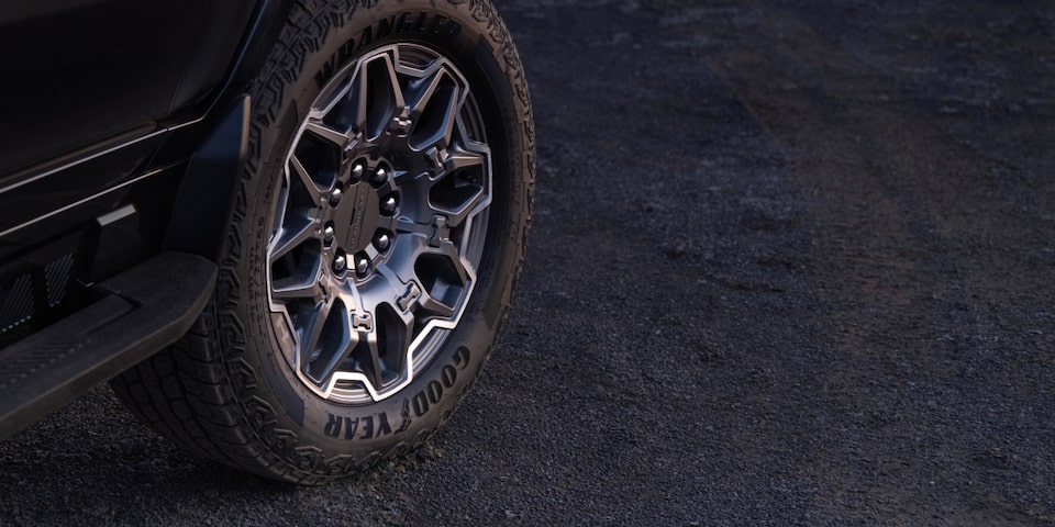 Close-up view of the front tire of a black 2025 GMC Hummer EV SUV.