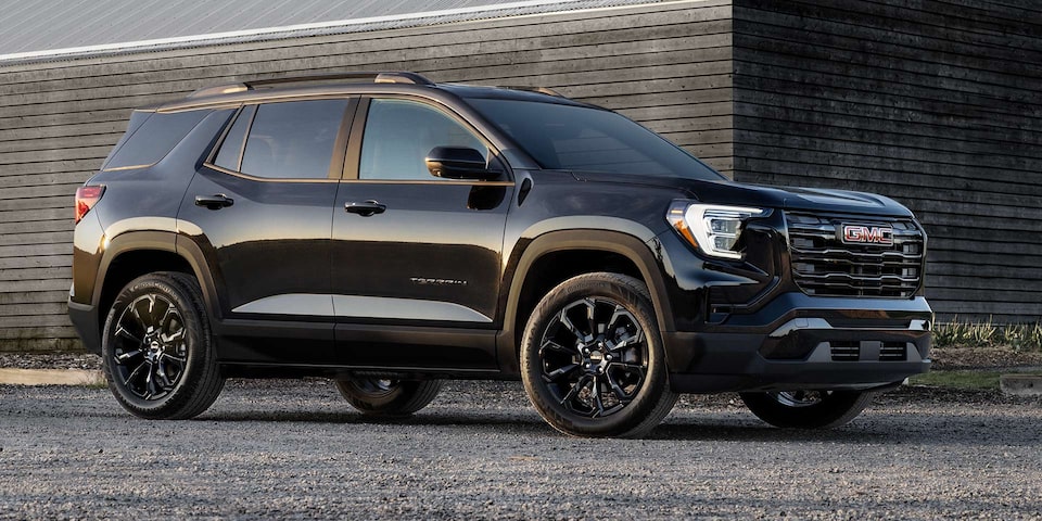 Front-side view of the 2025 GMC Terrain parked alone outside a wooden house.