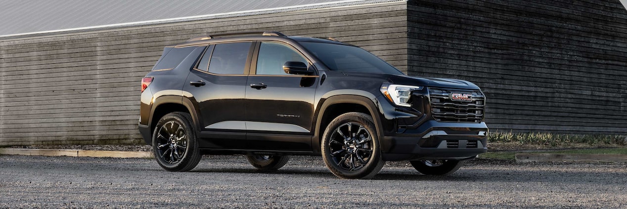 2025 GMC Terrain parked outside a wooden house.