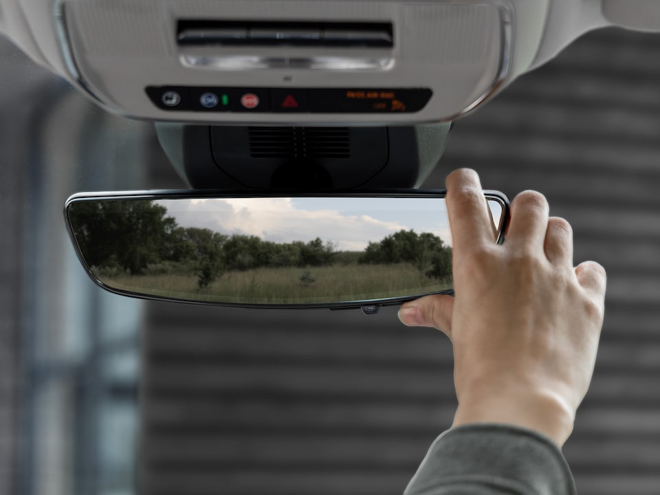 A person adjusting the rear view mirror inside the 2025 GMC Terrain.