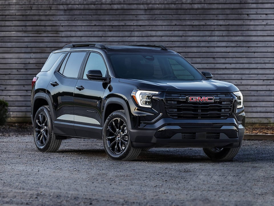 GMC Terrain 2025 stationné près d’une maison en bois.