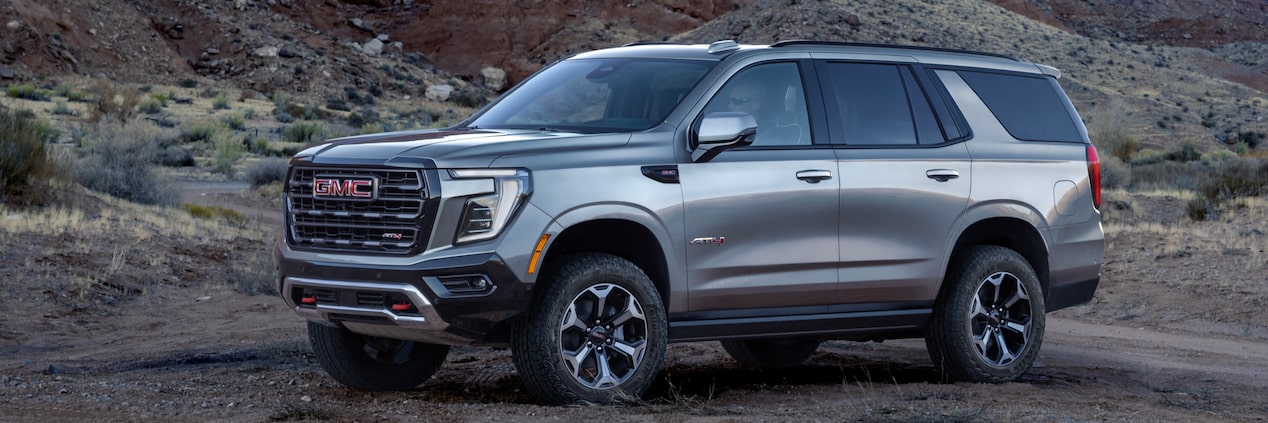 Vue latérale du GMC Yukon 2025 stationné devant une colline.