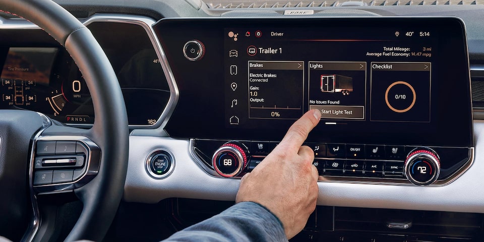 Close-up of a driver pressing the infotainment screen inside the 2025 GMC Canyon AT4.