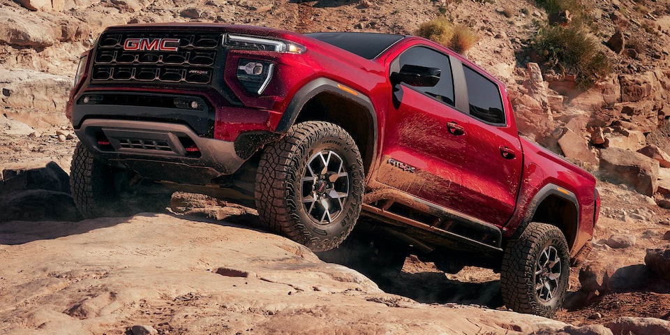 A 2025 GMC Canyon AT4 Driving Uphill Off-Road on Rocky Terrain.