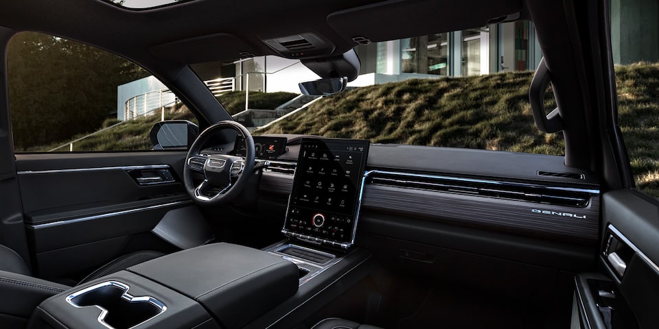 Front passenger's view of the interiors of the 2025 GMC Sierra EV Denali parked outside a building.