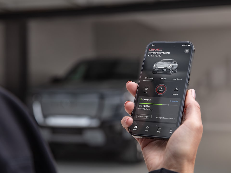 Une personne consulte de l’information sur le GMC Sierra EV Denali 2025 sur son téléphone intelligent.