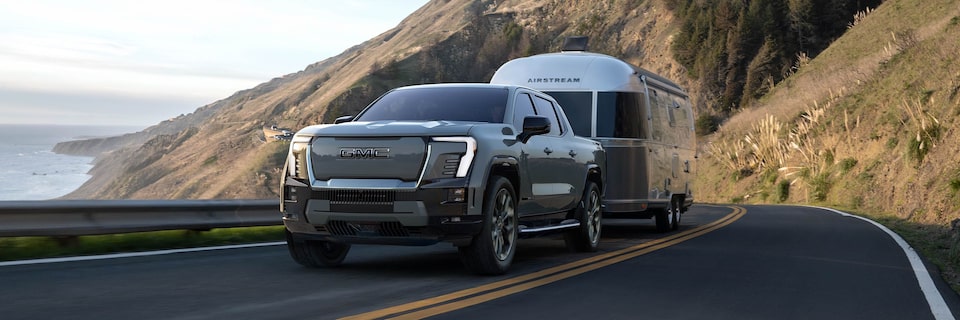 A 2025 GMC Sierra EV Denali towing a trailer on the road.