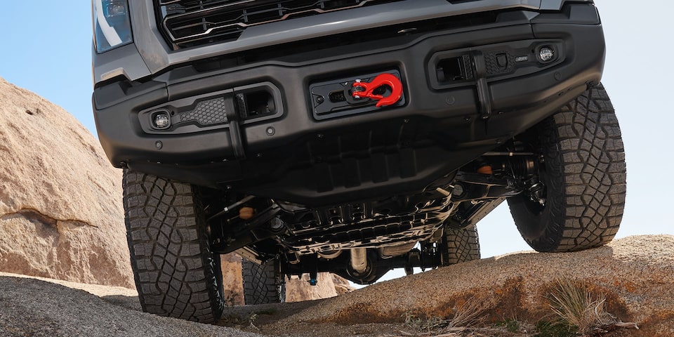 Close-up view of the trailer hook on a 2025 GMC Sierra HD AT4 truck driving on a rugged terrain.