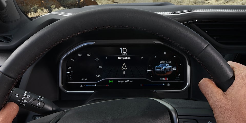 Close-up of a person's hand on the steering wheel of the 2025 GMC Sierra HD AT4 Truck.