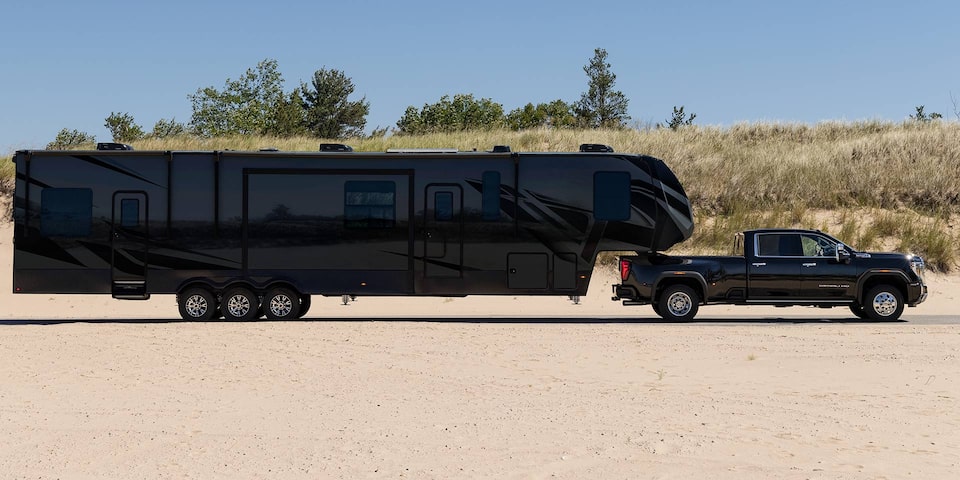 Wide Side View of a 2025 GMC Sierra HD Denali Truck Hauling a Trailer