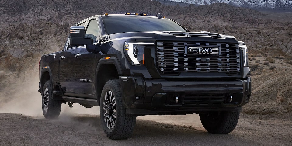 Front-side view of the 2025 GMC Sierra HD Denali Truck Driving Through the Desert.