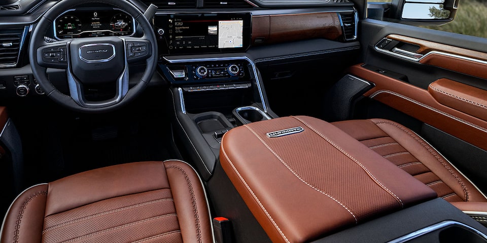 Close-up view of the Front Seats, Steering Wheel, and Infotainment System in a 2025 GMC Sierra HD Denali Truck.