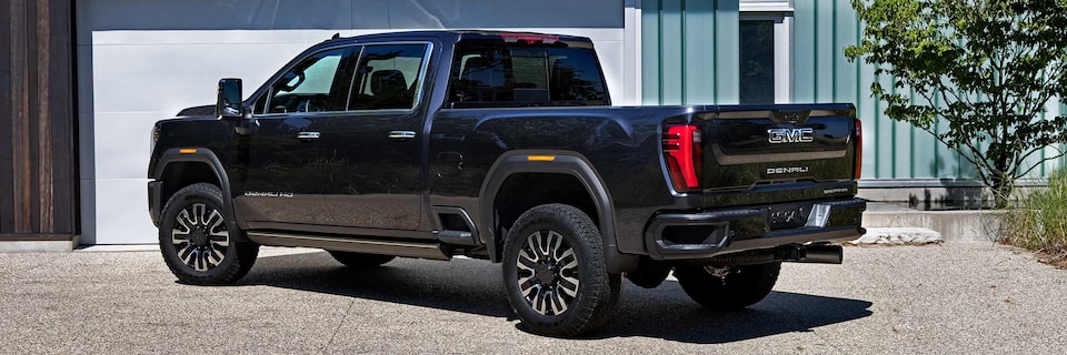 Back-side view of a 2025 GMC Sierra HD Denali Truck Parked on Gravel.