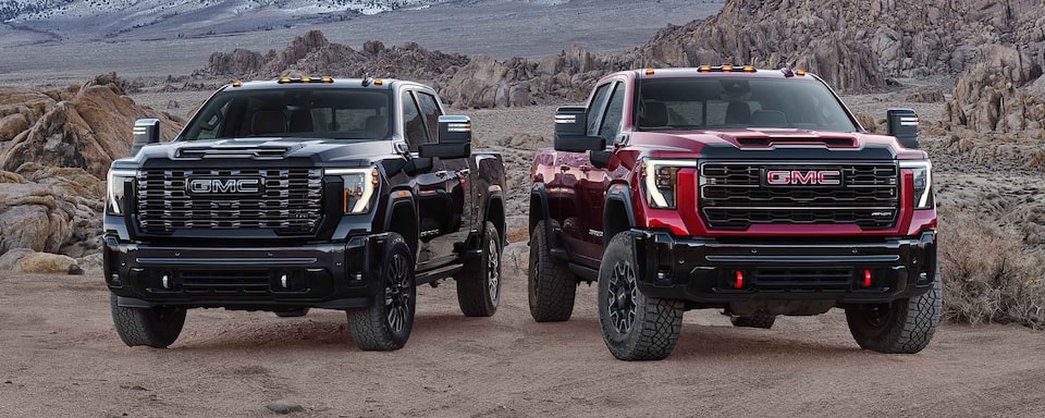 Two 2025 GMC Sierra HD Trucks Parked Side by Side with Mountains in the Background