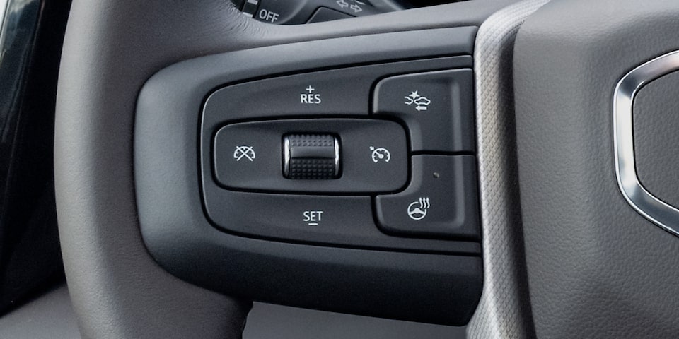 Close-up View of the Cruise Control Buttons on the Steering Wheel in a 2025 GMC Sierra HD Pro/SLE/SLT Truck.