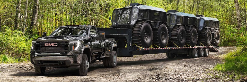 Vue élargie du camion GMC Sierra HD Pro/SLE/SLT 2025 qui remorque plusieurs véhicules.