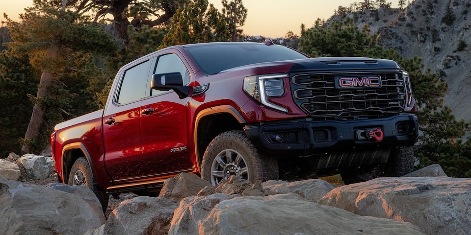 Red GMC Sierra 1500 Pickup Truck Driving Over Rocky Terrain