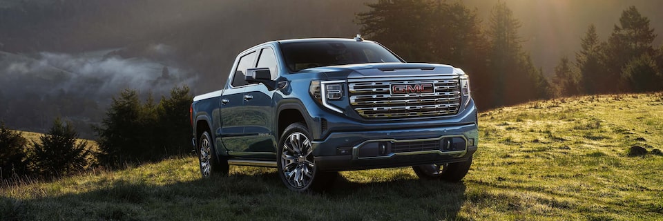 A Blue GMC Sierra 1500 Parked on a Hill as the Sun Shines Down on the Pickup Truck