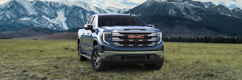 GMC Sierra 1500 Pickup Truck Parked in a Green Valley with Mountains in the Background