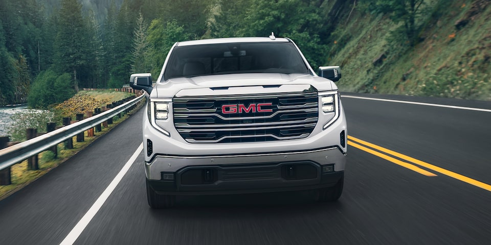 Front View of a White GMC Sierra Pickup Truck Driving Down the Road