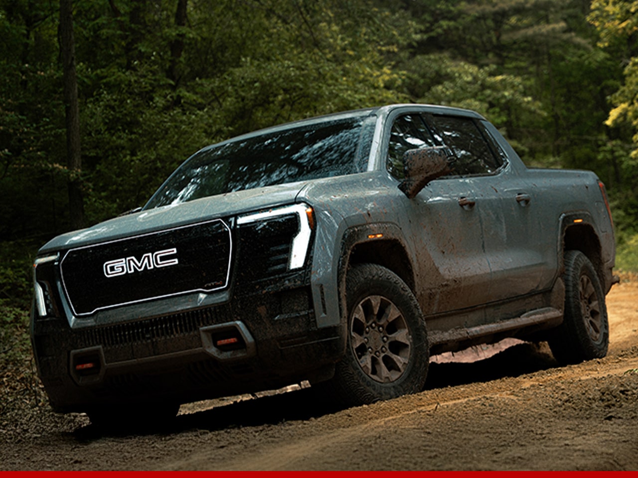 A GMC vehicle driving alone on a forest road.