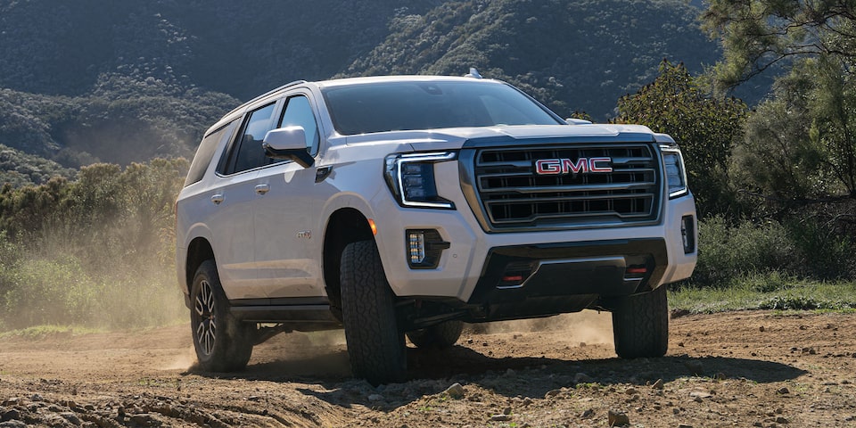 2024 GMC Yukon AT4 driving on dusty terrain.