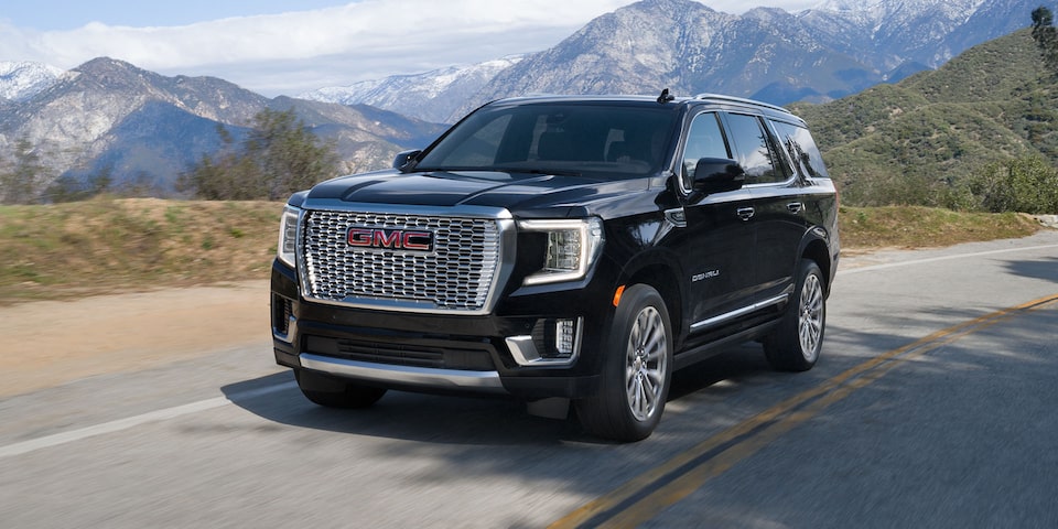 Front view of the 2024 GMC Yukon Denali driving alone on a road.