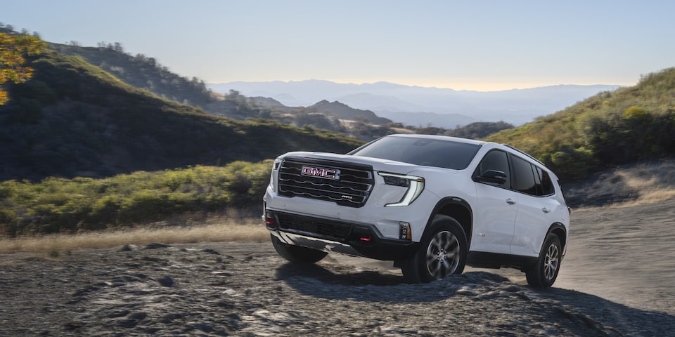 Vue latérale du GMC Acadia AT4 2025 roulant sur un terrain rocailleux.