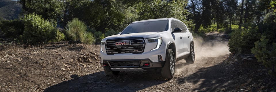 Front-side view of the 2025 GMC Acadia AT4 driving alone on a rocky terrain.