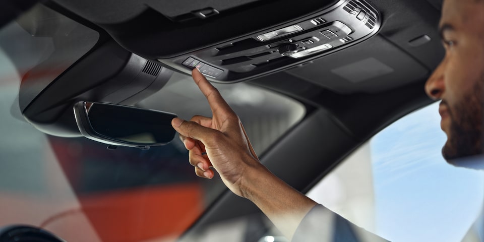 A person pressing a button inside the 2025 GMC Acadia AT4.