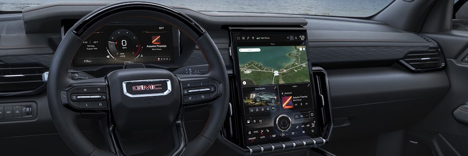 Le volant et l’écran du système d’infodivertissement du GMC Acadia AT4 2025 vus par le conducteur.