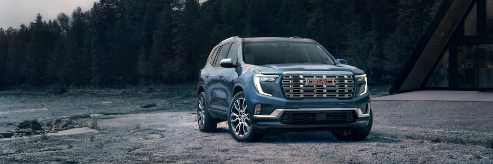 A 2025 GMC Acadia Denali parked alone outdoors during a gloomy weather.