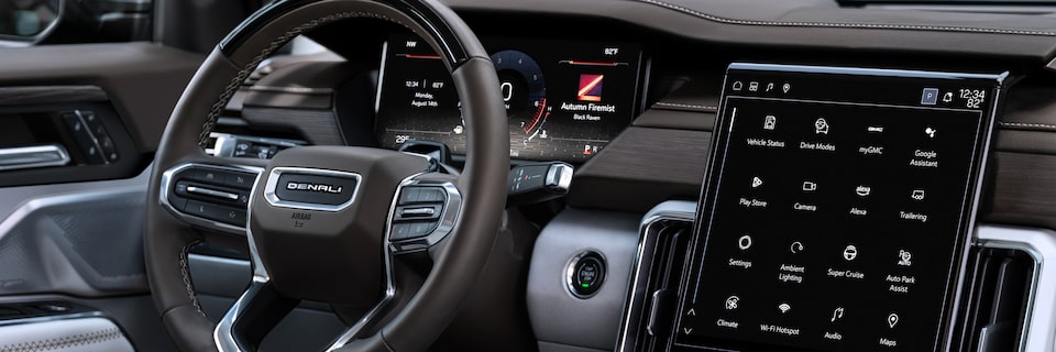 Side view of the steering wheel and infotainment screen of the 2025 GMC Acadia Denali.