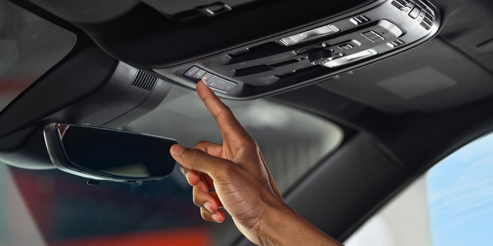 A person pressing the button inside the 2025 GMC Acadia Denali.