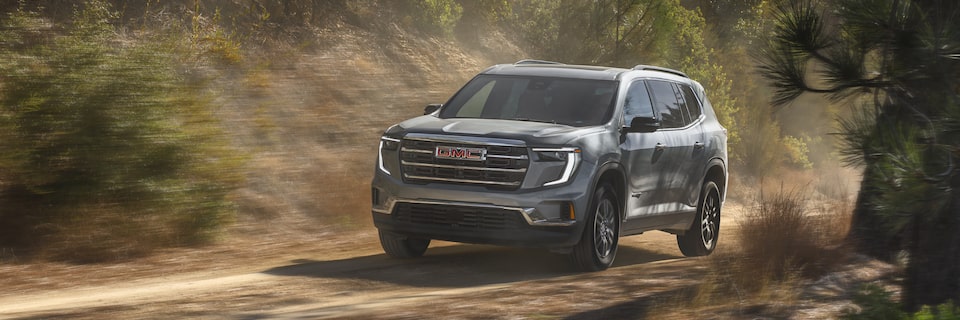 2025 GMC Acadia Elevation driving fast on a countryside road.