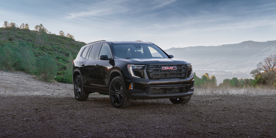 Front-side view of the 2025 GMC Acadia Elevation parked alone outdoors near trees.