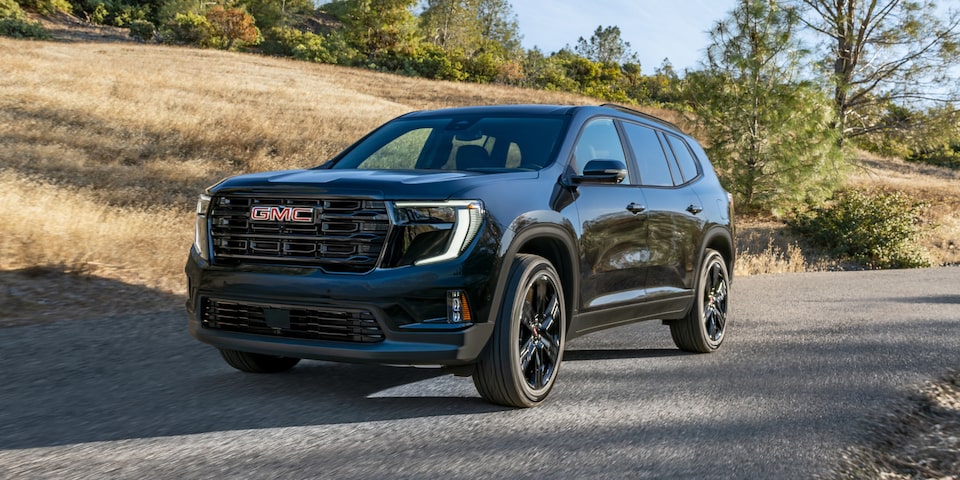 Side view of the 2025 GMC Acadia Elevation driving on the road on a sunny day.